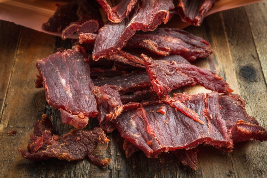 close up picture of beef jerky on a wood plank